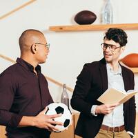 portrait of multiethnic businessmen with soccer ball and book in cafe sport business