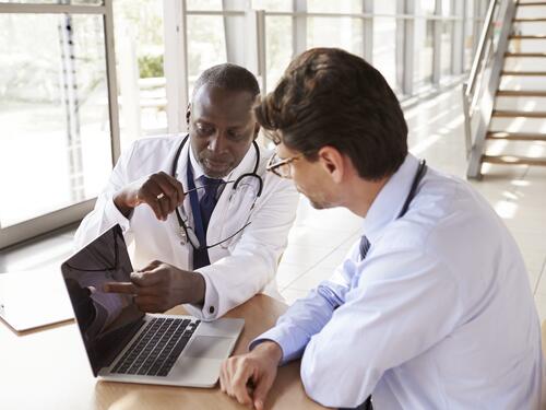 Two senior healthcare workers in consultation using laptopq