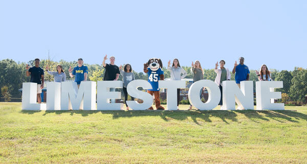 Students standing in front of the Limestone lettered sign