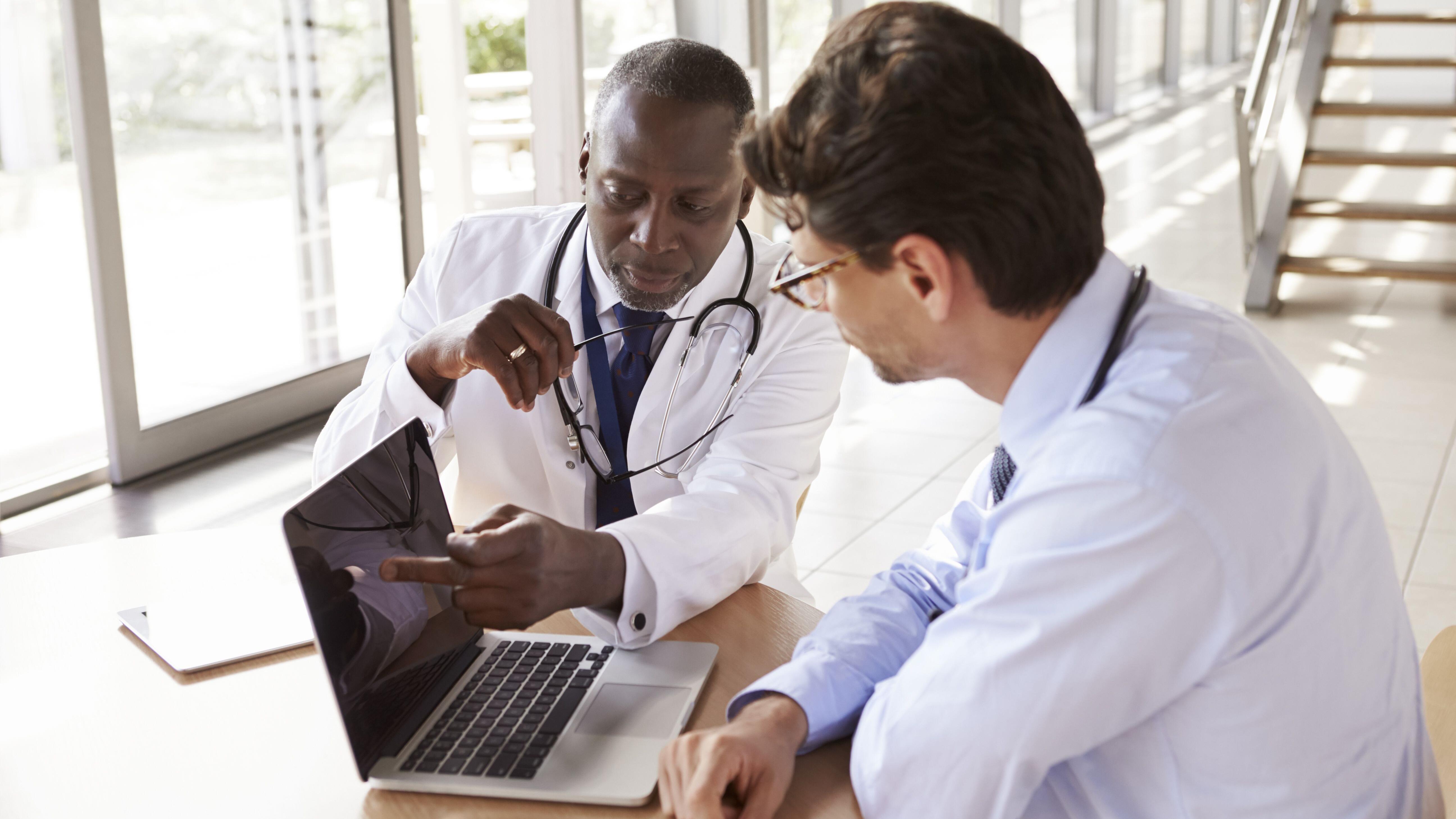 Two senior healthcare workers in consultation using laptopq