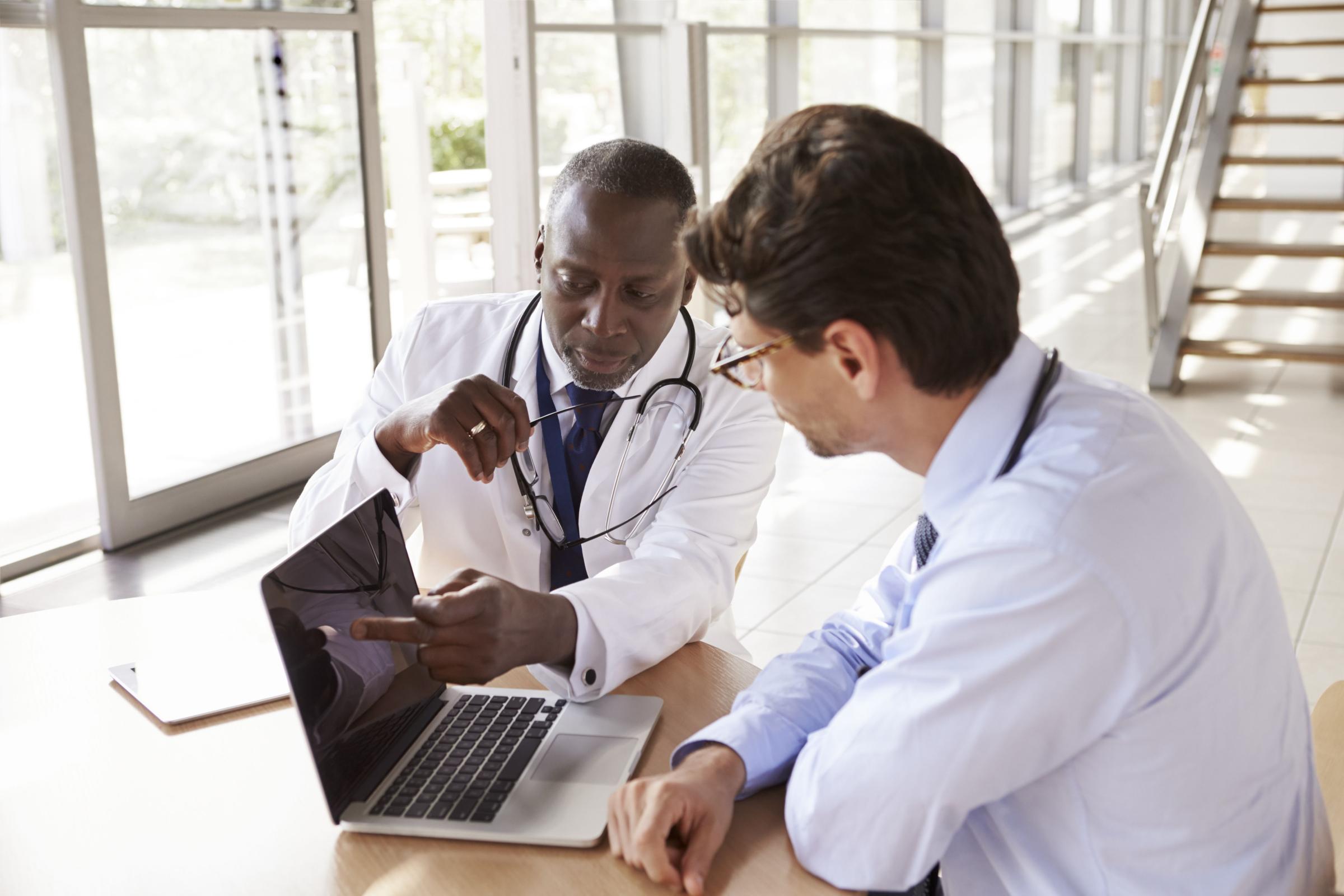 Two senior healthcare workers in consultation using laptopq