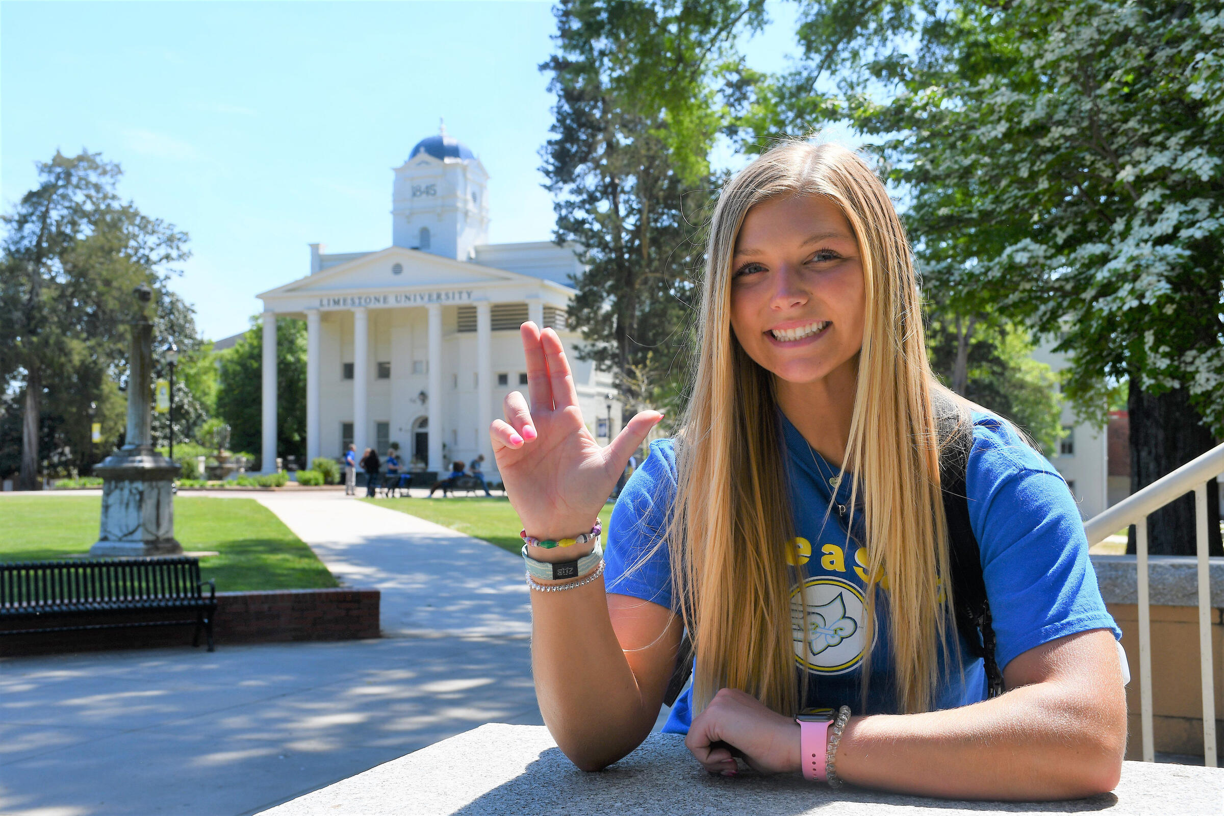 Student throwing L in front campus