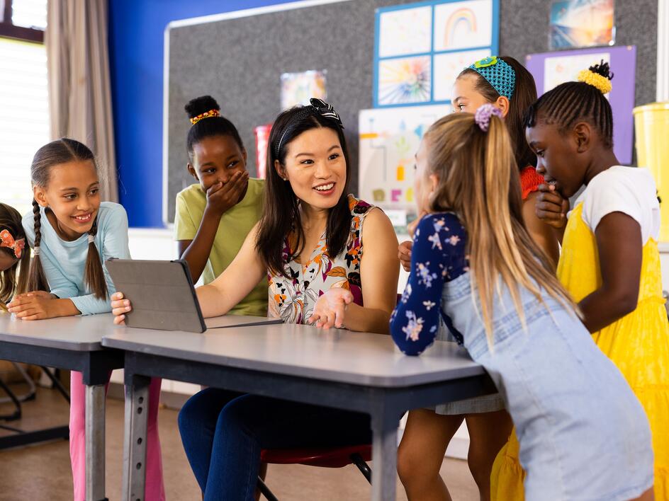 Diverse female teacher with tablet and elementary schoolgirls in class